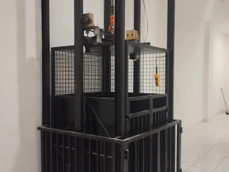Lift barang custom terpasang di ruko grosir Jakarta Utara, tampak rangka baja hitam dan sangkar mesh