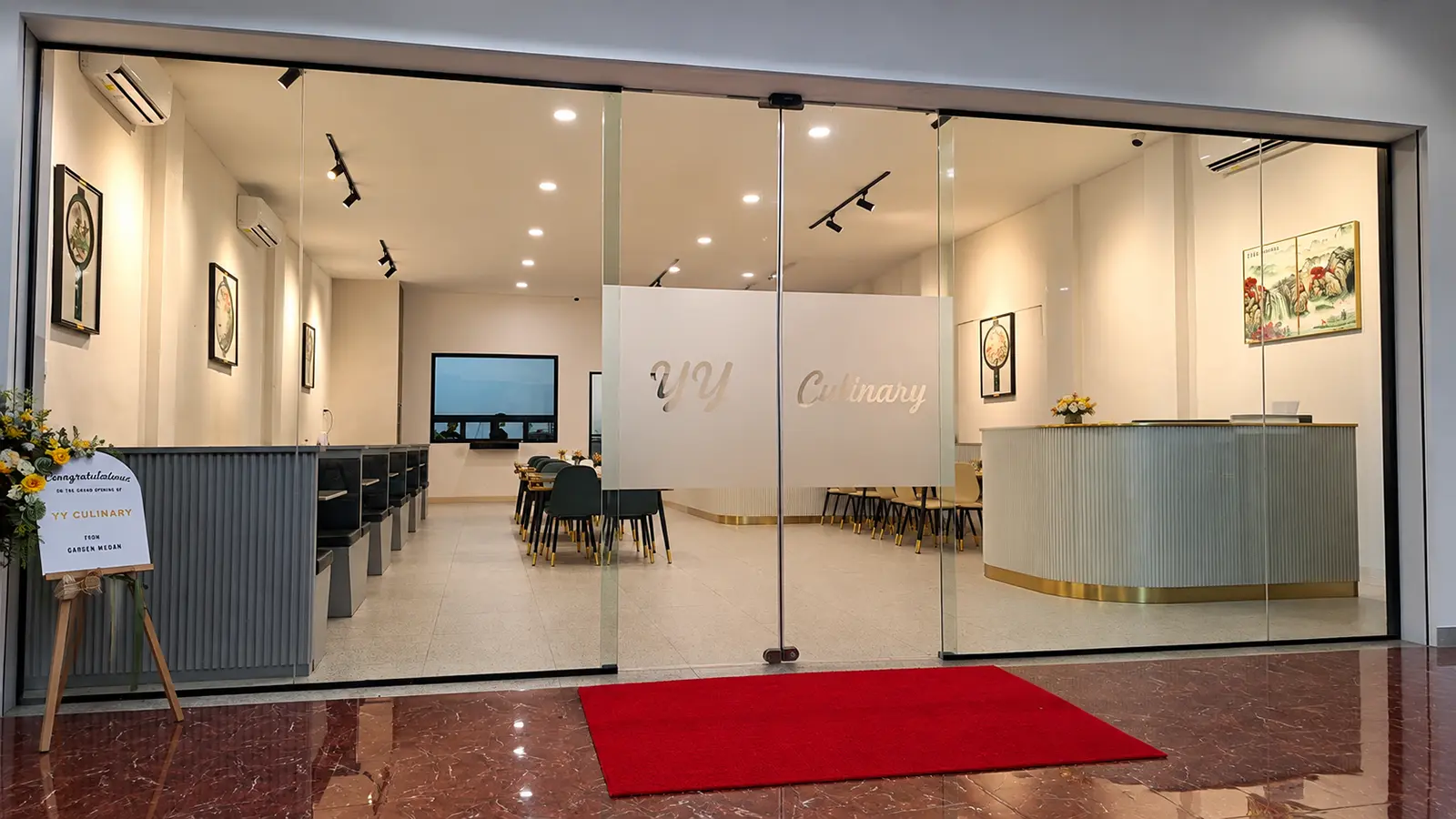 Pintu geser otomatis kaca frameless di fasad depan YY Culinary Medan, diapit panel kaca mati di kedua sisi