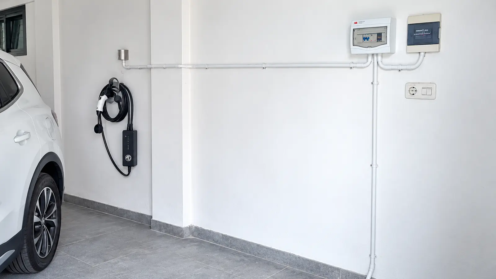Colokan khusus portable charger mobil listrik di lantai dasar Ruko MMTC Medan, dengan box MCB di dinding dan jalur pipa konduit menuju titik parkir mobil